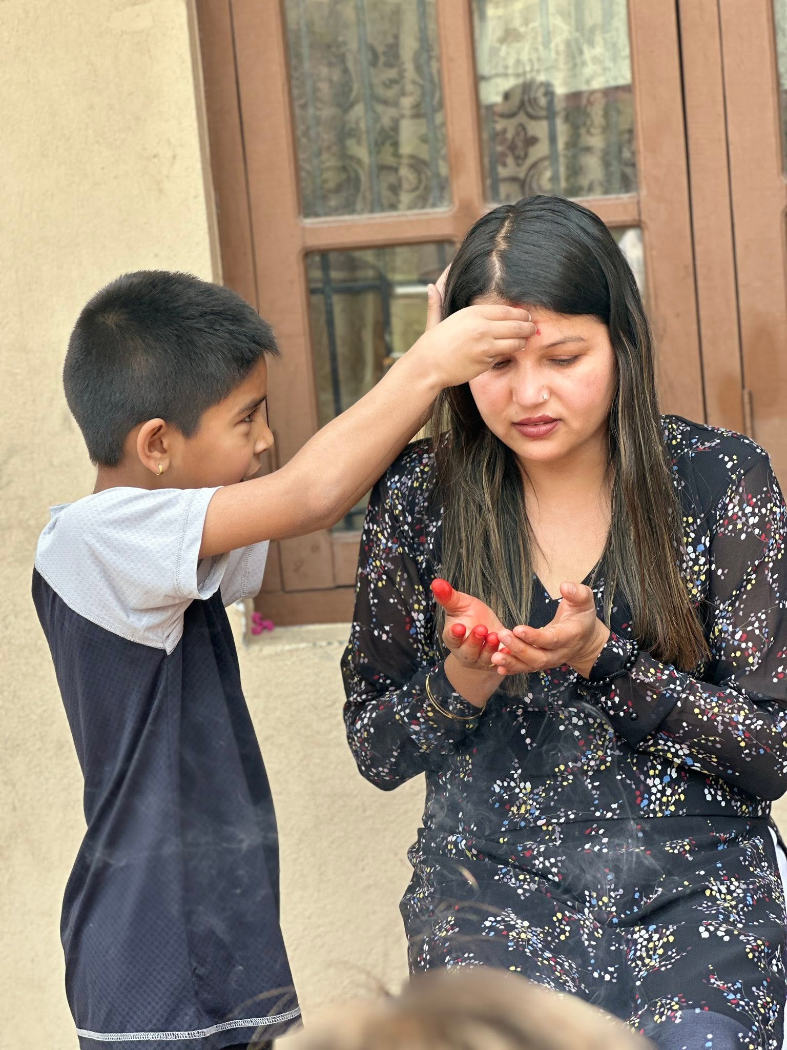 Child putting tika on caregiver